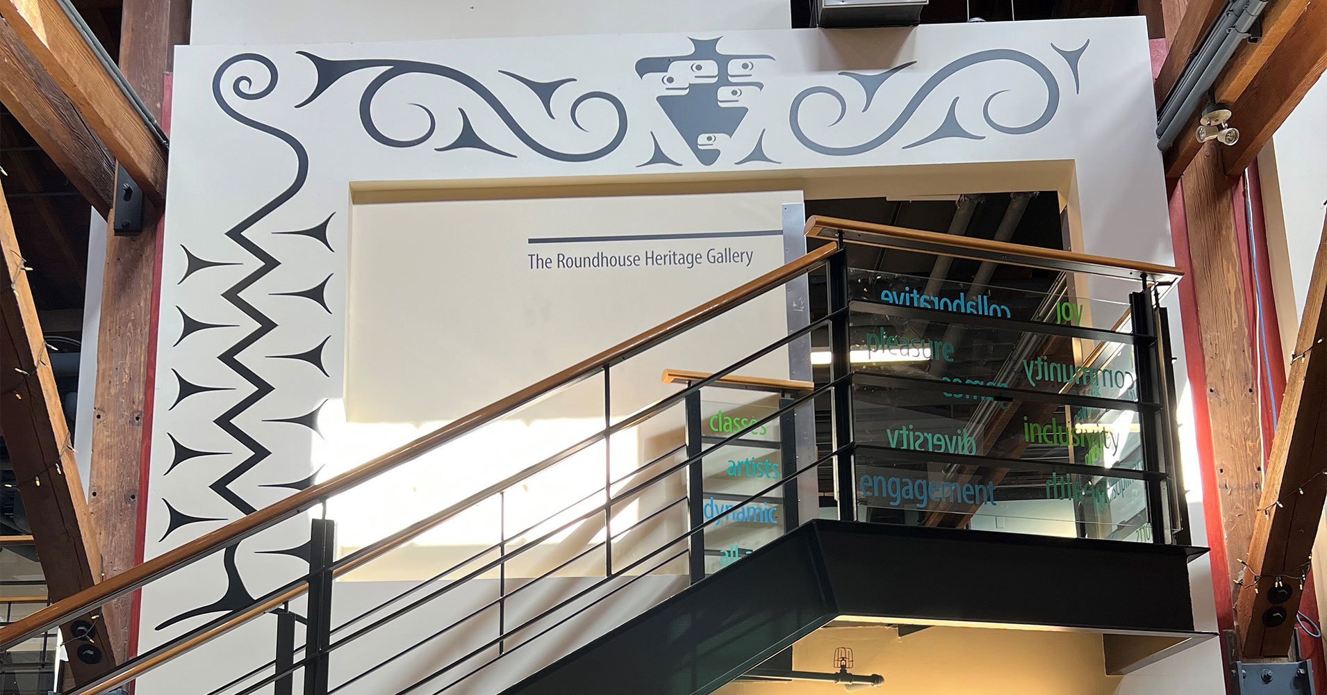 Interior of the Roundhouse: the entrance to the mezzanine level at the top of the stairs is framed by Indigenous artwork on the wall